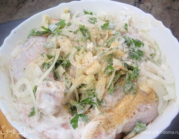 Курицу разрезать по грудине на пополам. Натереть чесночком, солью и хмели-сунели. Лук немного помять в руках и положить в миску к курице. Добавить сметану и зелень, перемешать. Положить сверху тарелку и гнет. Оставить мариноваться на сутки. 