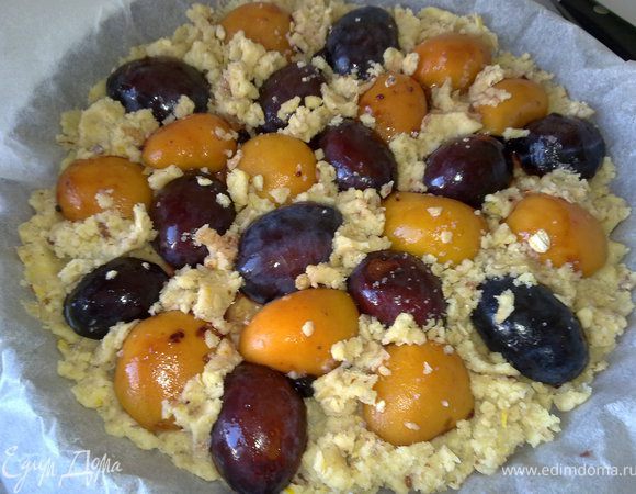 Смешать крупу, муку, сахар, масло, орехи, цедру лимона. Форму застелить бумагой для выпечки, выложить в форму 3/4 теста, затем сверху выложить сливы и абрикосы.  Поверх ягод (кабы между ними)  равномерно распределить остатки теста.