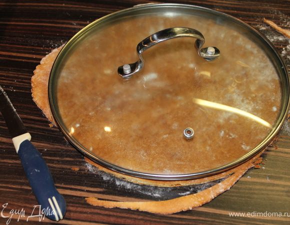 Достаем корж из духовки и пока теплый ровняем края по крышке (или большой тарелке) с помощью ножа.