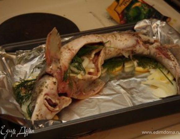 Положите на подушку рыбу. Из-за большого размера пришлось ее слегка завернуть. Те же ингредиенты положите ей в брюхо и сверху.