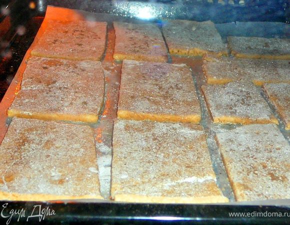 Разделить тесто на две половины,вторую половину отправить опять в холодильник.А первую раскатать на присыпанной мукой поверхности в прямойгольник толщиной 0,3-0,4см.Обрезать края.Нарезать на прямоугольники,сделать вилкой несколько наколов.Переложить на противень застеленный смазанным сливочным маслом пергаментом.Присыпать сахаром и молотой корицей.Выпекать в разогретой до 150гр.духовке 15минут.Все тоже проделать и со второй частью теста.Дать остыть крекерам. 
