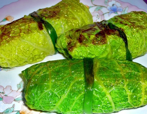 Рис промываем и отвариваем до полу-готовности.Морковку натираем на терку,лук режим кубиками,слегка обжариваем на растительном(оливковом)масле лук и морковь.Разбираем капусту на листья.У листьев срезаем утолщения,заливаем их небольшим кол-вом горячей,подсоленной воды и бланшируем минуты 2-3.В мясной фарш добавляем отваренный до полу-гостовности рис,половину обжаренной моркови и лука,яйцо,соль,перец,зубчик измельченного чеснока,рубленную зелень перемешиваем.В листья заворачиваем фарш,формируя голубец,завязываем каждый голубец перышком ошпаренного,зеленого лука.В жаровне распускаем топленое масло и обжариваем со всех сторон голубцы.Затем добавляем к ним оставшуюся морковь и лук,заливаем бульоном,накрываем крышкой и тушим минут 45.Я тушила в духовке и за 20 минут до окончания приготовления добавила в голубцы сметану. 
