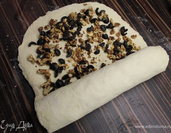Выложить орехи и оливки. И скатать рулетом, начиная с узкой стороны. Бока закрыть, подвернув немного вниз.