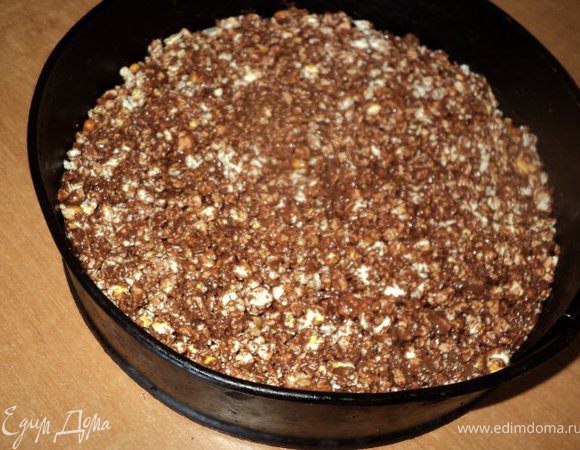 Молочный шоколад и 50 гр черного шоколада разломать на кусочки и растопить на водяной бане. Взять разъемную форму для тортов, на дно положить бумагу для выпечки. Попкорн измельчить, добавить растопленный шоколад, перемешать, выложить в форму, уплотнить ложкой, поставить на 10-15мин в холодильник.