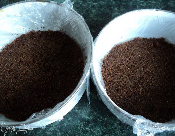 Чиз-кейк можно формировать в разъемной форме диаметром 26см, но я взяла две меньшего размера ( 18см). Дно разъемной формы застелить бумагой для выпечки или пищевой пленкой. На дно формы выложить подготовленные сухарики, уплотнить ложкой и поставить в морозилку на 15 мин.