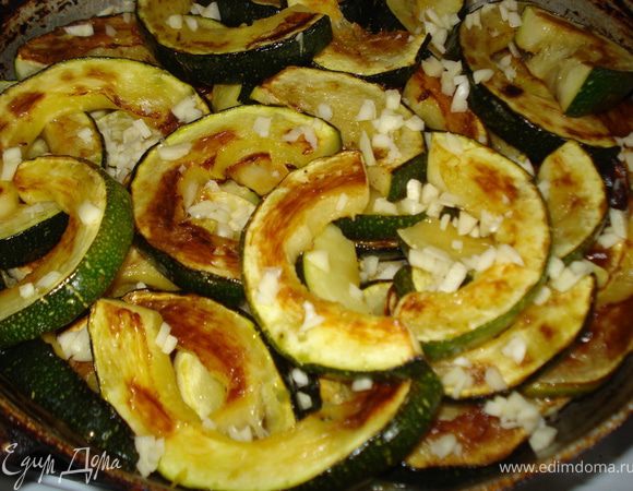 Укладываем на противень или как я в сковороду со съемной ручкой. Чистим чеснок, нарезаем мелко, посыпаем сверху кабачки.
