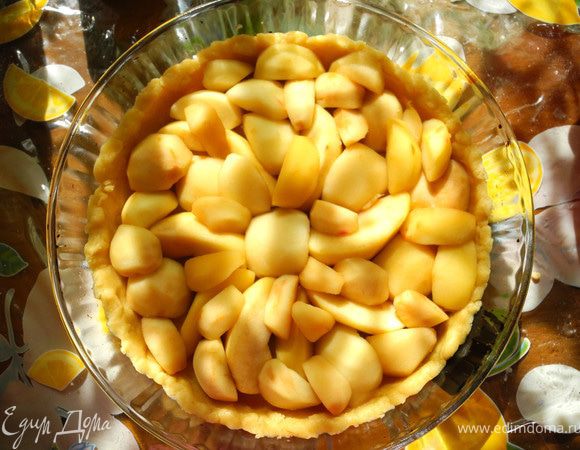 После этого яблоки аккуратно выложить на дуршлаг, чтобы жидкость стекла. Тесто вынуть из холодильника, дать немного "согреться". Затем распределить по форме, разминая руками. Сделать небольшие бортики. Уложить  на тесто яблоки.
