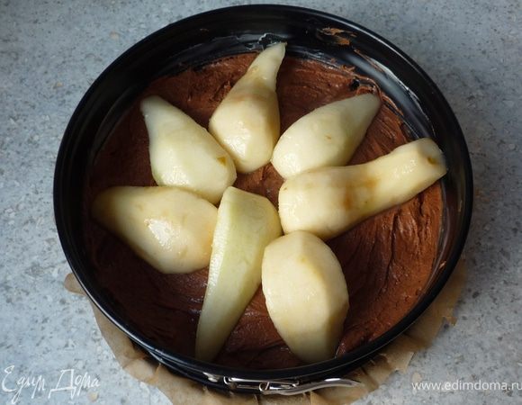 Выложить тесто в разъемную форму, смазанною маслом и выложенную бумагой для запекания. Сверху разложить груши. Запекать пирог в предварительно разогретой до 175°C духовке ок. 70 минут.