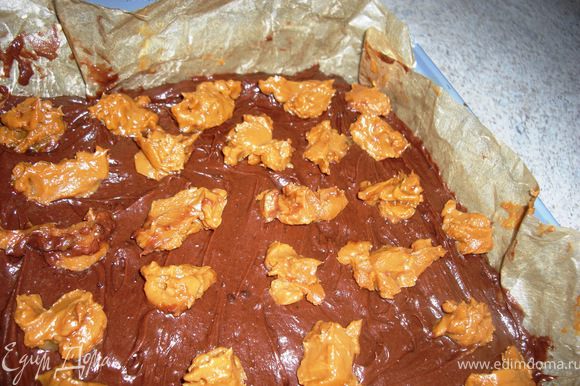 Выложить шоколадноe тестo в форму, разгладить поверхность и разложить по немного карамели.