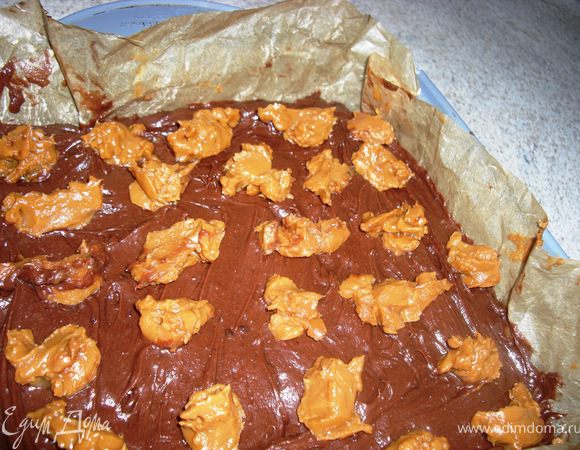 Выложить   шоколадноe  тестo  в форму,  разгладить поверхность и  разложить по  немного карамели.