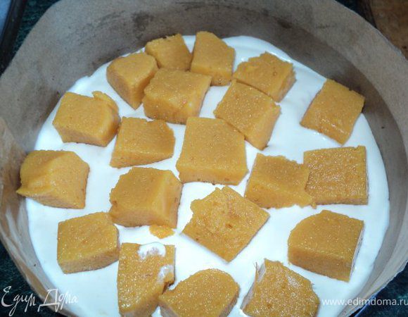 На корж вылить половину крема, выложить порезанное кубиками персиковое суфле,