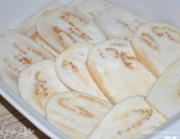 2 баклажана очистить, порезать вдоль на пластины и уложить на дно формы. Посолить, поперчить.