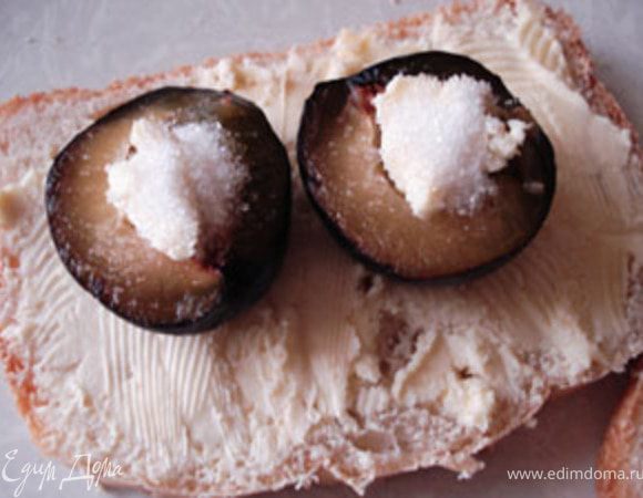 Ломтики хлеба намазать сливочным маслом,сверху положить половинки слив. Вместо ядра положить кусочки масла и 1/4 части сахарного песка. Запечь в духовке до готовности.