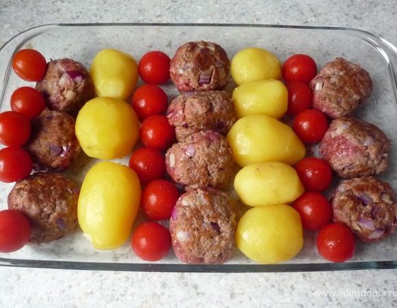 Картофеть почистить.Форму для запекания смазать маслом. Выложить в нее слоями картофель, тефтельки и томаты черри. 