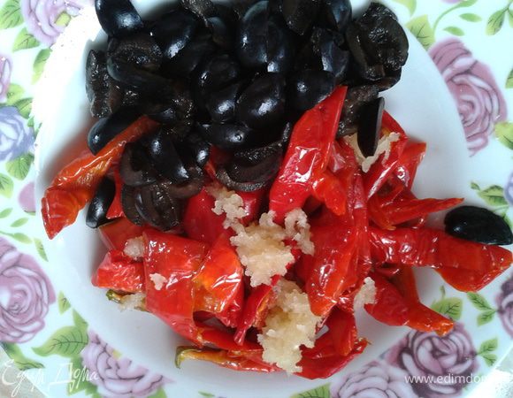 Готовим начинку. Перец некоторое время подержать на сите, чтобы стекло масло. Это масло можно использовать в тесте (там где 50 мл.) Почистить чеснок, подавить. Маслины порезать пополам. Перемешать с перцем. 