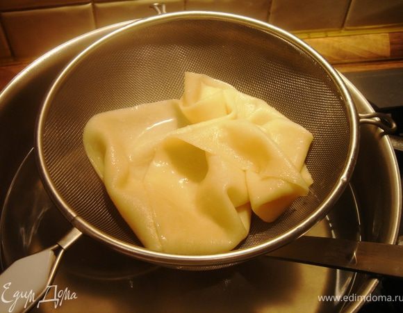 Аккуратно шумовкой подцепите лист теста и переложите в сито.