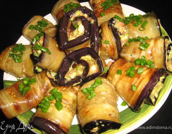 Баклажаны разрезать вдоль,на пластины,посолить и положить под пресс на 30 минут,что бы ушла горечь.
Разогреть небольшое кол-во раст.масла на сковороде и обжарить баклажны с двух сторон до золотистого цвета. 
Пока баклажаны остывают приготовим начинку.
Авокадо очистить от кожи и косточки,мякоть сбрызнуть лимонным соком и размять(или натереть на тёрке).
Мясистый,крепкий помидор разрезать пополам,удалить семечки и сок,мякотоь натереть на тёрке(без кожицы),зелёный лук очень мелко нарезать,все ингридиенты размешать(можно измельчить с помощью блендера),послить,поперчить по вкусу.На баклажан положить чайную ложку начинки,свернуть рулетиком.Охладить.Приятного аппетита!