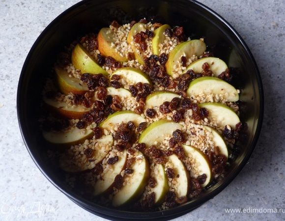 Сверху распределить яблоки, посыпать орешками и изюмом.