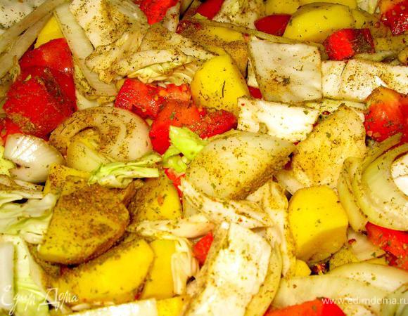 За это время почистить овощи (картофель, морковь, лук, капусту, помидоры). Нарезать небольшими кусками произвольной формы. Выложить все в глубокий противень, приправить морской солью, черным перцем, тимьяном, паприкой и куркумой. Тщательно перемешать.