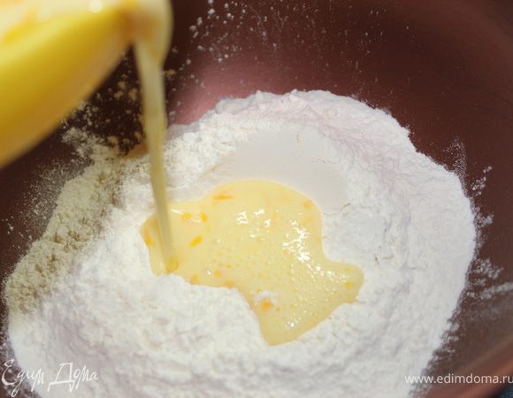 Молочно-яичную смесь влить в муку. Хорошенько все перемешать. Тесто липнет к рукам, я присыпывала мучкой и потом перед укладкой на стеклянный поддон смазывала руки в растительном масле, чтобы можно было спокойно уложить тесто и, чтобы оно не прилипало к рукам.