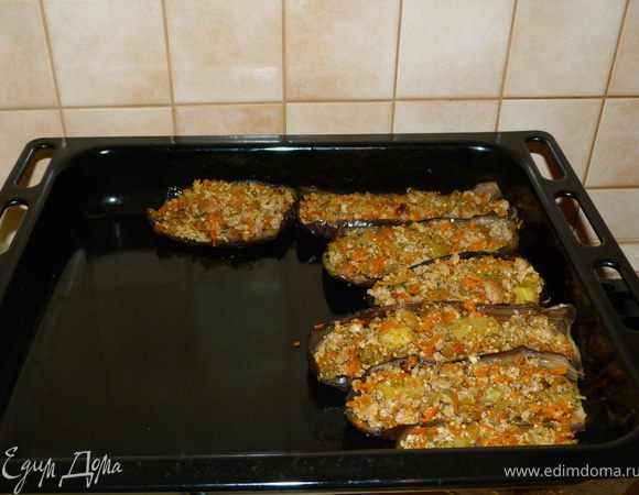 На противень выкладываем подготовленные ранее половинки баклажан и наполняем их начинкой. Кладём их тесно, чтобы они помогали друг другу держать форму.
