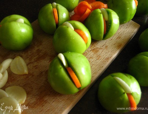 Морковь режем колечками,чеснок разрезаем каждую дольку вдоль на 4 части. Помидоры разрезаем пополам на 2/3  и в разрез вставляем кружок моркови и кусочек чеснока. Укладываем плотно в банку.