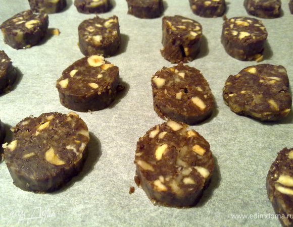 Колбаски вынуть из холодильника и дать им немного полежать (минут 5-7). Иначе я начала резать и они начали крошиться. Колбаски нарезать кружочками толщиной не боле 1 см ( в оригинале 0,5 см) горячим ножом. И выложить на противень с пекарской бумагой.