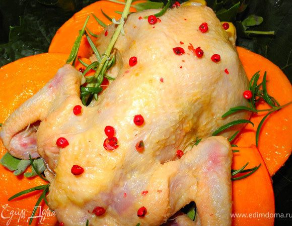 Смазать тыкву смесью меда и масла, слегка посолить, положить в форму, накидать сверху шалфей и розмарин. Уложить на эту "подушку" цыпленочка, посыпать розовым перцем. Выпекать при температуре 200 градусов 10 минут и потом еще 20-30 минут в зависимости от веса цыпленка.