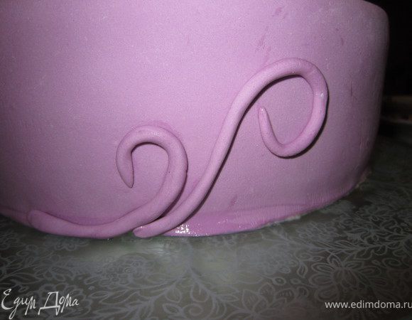 Из остатков мастики сделать тоненькие жгутики, прикрепить к торту.