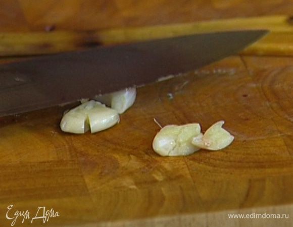 Чеснок почистить, раздавить плоской стороной ножа и добавить к луку, перемешать и обжаривать еще 2–3 минуты, затем посолить и поперчить.