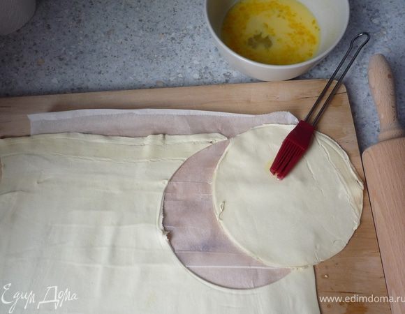 Разморозить зеленый горошек. Если тесто замороженное, то оставить его при комнатной температуре минут на 10. После разморозки необходимо раскатать каждый лист и получить из него 2 круга 14см в 
диаметре (итого 12 кругов). У меня листы теста большие, но их необходимо было немного раскатать, буквально на пару-тройку см. Смешать 1 яйцо и молоко и каждый круг из теста смазывать этой смесью.