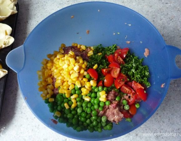 Дать стечь воде с кукурузы. Томаты черри помыть и нарезать на четвертинки. Петрушку порубить. Кукурузу, томаты, петрушку и горошек добавить в фарш и перемешать.