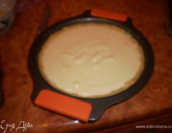 В форму выложить тесто, распределить, сформировать бортики. Вылить крем.