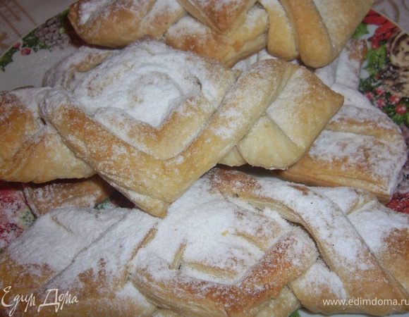 Тесто нарезать на квадраты и на каждом квадрате сделать надрезы в углах и сделать нахлёст друг на друга,прикрывая начинку из рикотты(на каждую ватрушку по 1 ложки рикотты.Смазать взбитым яичным желтком.
 Поставь в духовку 180 г./20 мин/до золотистого цвета.Вытащить и посыпать сах.пудрой.