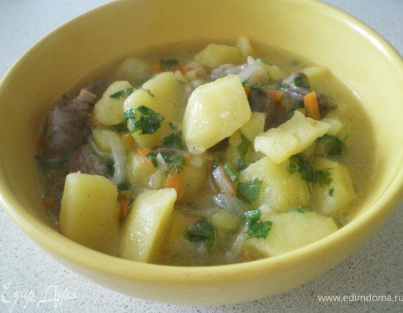 Картофель, нарезанный ломтиками залить бульоном и поставить варить. Сердечки вымыть, положить на сковороду с растительным маслом и обжарить. Затем добавить натёртый на тёрке морковь и нарезанный лук. Обжаривать ещё 5-7 минут. Затем переложить к картофелю, посолить. Добавить мелко нарезанную зелень. Варить до готовности. 