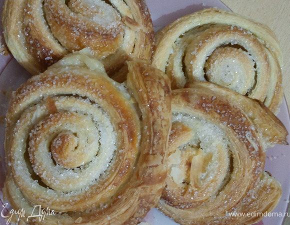 Готовое слоеное дрожжевое тесто раскатать, намазать пласт растительным маслом и посыпать сахарным песком ( по вкусу). Свернуть рулетом и нарезать. Поставить в духовку  и выпекать при 180 градусах около 20-30 минут.