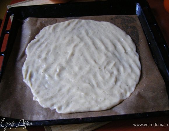 На пергамент смазанный растительным маслом выкладываем половину теста и распределяем в виде лепешки руками. Руки каждый раз при касании теста смачиваем в воде.