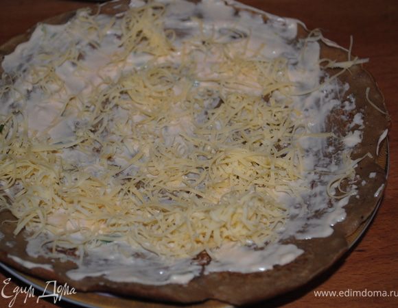 Выложить на тарелку один блин, смазать майонезом и посыпать сыром