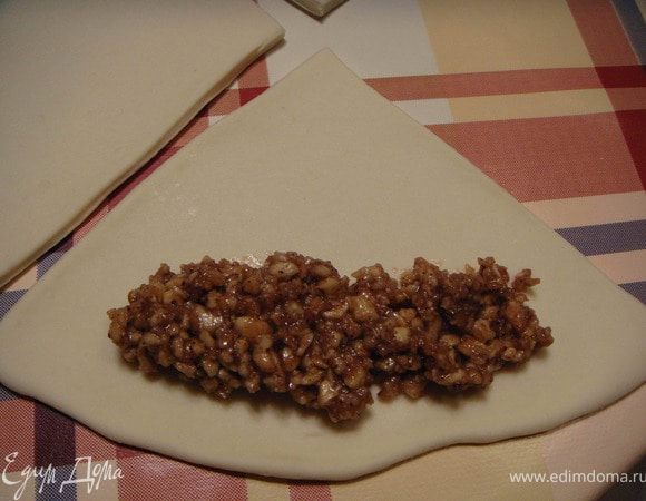 Когда расстойка теста будет окончена, выкладываем тесто на посыпанную мукой поверхность и слегка обминаем. Делим тесто на 2 части. Каждую часть раскатываем, разрезаем на 4 сектора и выкладываем начинку.Скручивам жгутиком и защипываем.