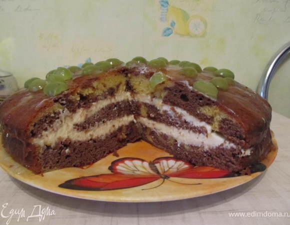 Выпеченый бисквит перерезать пополам и смазать сметанным или сливочным кремом (сметану взбить с сахаром и ванилином) Сам бисквит очень сладкий, поэтому я сыпала меньше сахара, чтобы кислинка была. Готовый торт полить шоколадной глазурью или как у меня украсить виноградом и полить желе для торта.