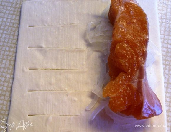 Из 4 пластиков теста сделать слоечки-"лопнувшие трубочки". Левую половинку пластика надрезать поперек через 1.5 см. А на правую половинку выложить лук и рыбу.