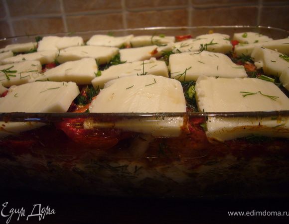 Достаём форму из духовки, сбрызгиваем пряным соусом, посыпаем укропом и накрываем пластиками моцареллы. 