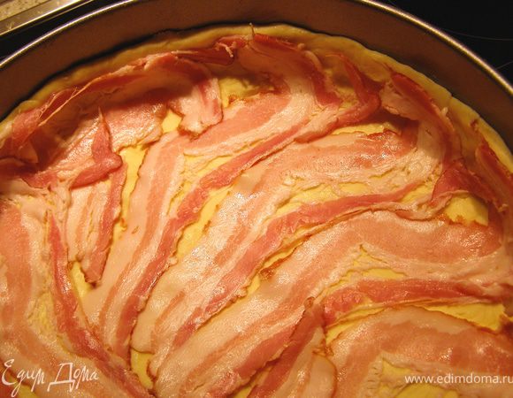 На тесто выложить бекон, стараясь закрыть всю поверхность.