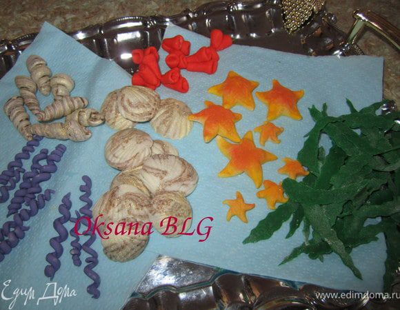 Из зеленой мастики произвольно вырезать полосочки для зеленых водорослей. Оставить все украшения сохнуть.