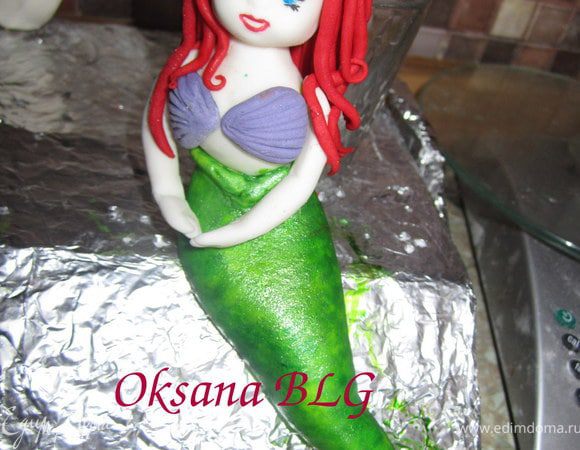 Прикрепить руки на капельку воды. И голову. Для того что бы сделать волосы, сделать тоненькие жгутики из красной мастики и по одному прикрепить к голове.