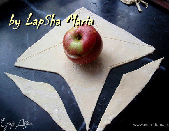 Из теста делаем два квадратика, в центр которых кладем по яблоку. С каждого края вырезаем треугольники как на фото.
