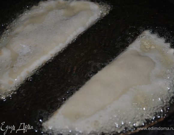 Тесто разделить на кусочки величиной с шарик для пинг-понга, тонко раскатать, положить ложку фарша, распределить по тесту, сложить пополам и обрезать край ножом. Жарить в большом количестве разогретого растительного масла на среднем огне до румяного цвета.