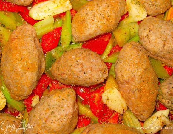 Теперь достаем наш охлажденный фарш и лепим полпеттини. Форма может быть любой, хотите круглые, хотите, как я, немного вытянутые. Выкладываем их равномерно поверх овощей в противень. Зубчики чеснока раздавить ножом и разложить между полпеттини.