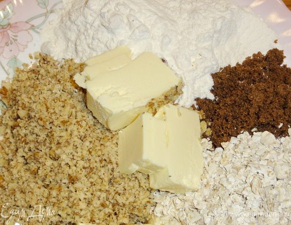 Орехи измельчите в блендере.
Масло желательно предварительно подержать в морозильной камере и порезать кусочками.
Из масла, сахара, муки, хлопьев и орехов  приготовьте крошку. 