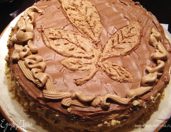 Наносим на поверхность торта каштановую веточку тонким контуром. Для этих целей я пригласила своего сына, он отменно рисует. А потом кремом повторяем контуры. Или можно Маленькой металлической лопаточкой (художественным мастихином, к примеру) нанести крем по всей поверхности внутри контура и "продавить" прожилки листиков. Я решила и эту часть работы сыну поручить, но ребёнок мой решил, что крем слишком застыл и поставил его в микроволновку подогреть! Естественно, крем расслоился, это видно.